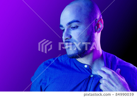 Young black man takes off the shirt in neon light Young black man takes off the shirt in neon light 84990039