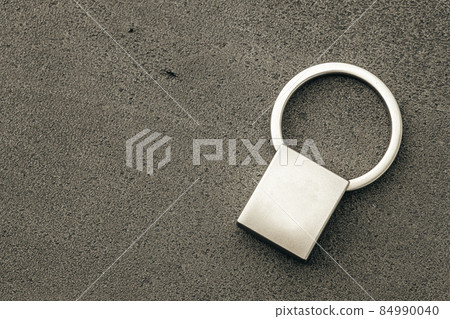 Metal key pendant on dark concrete background Metal key pendant on dark concrete background 84990040