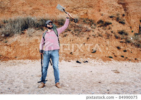 Male with metal detector found something on the beach 84990075