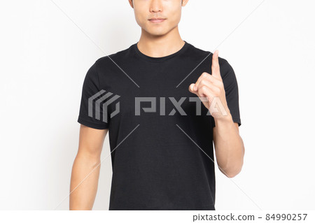 Young man wearing a black t-shirt standing in front of a white background and showing points Young man wearing a black t-shirt standing in front of a white background and showing points 84990257