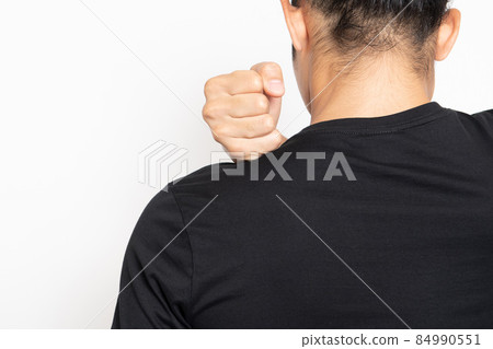 穿著黑色 T 恤的年輕人站在白色背景前,摸著他的肩膀 穿著黑色 T 恤的年輕人站在白色背景前,摸著他的肩膀 84990551