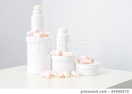 Cosmetic skincare packaging. Beauty product on white background. White jars with marshmallows on the white table. Cosmetic skincare packaging. Beauty product on white background. White jars with marshmallows on the white table. 84990878