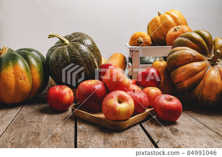 Pumpkins and red apples on wooden background Pumpkins and red apples on wooden background 84991046