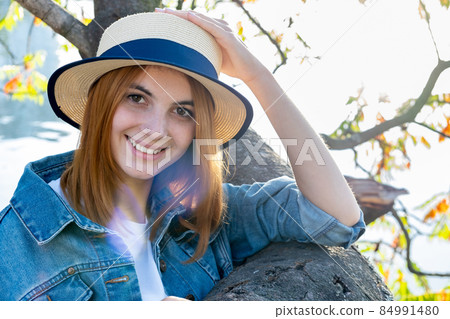 Portrait of gorgeous smiling teenage girl in yellow hat and with red hair wearing geans jacket outdoors on sunny autumn day. Portrait of gorgeous smiling teenage girl in yellow hat and with red hair wearing geans jacket outdoors on sunny autumn day. 84991480