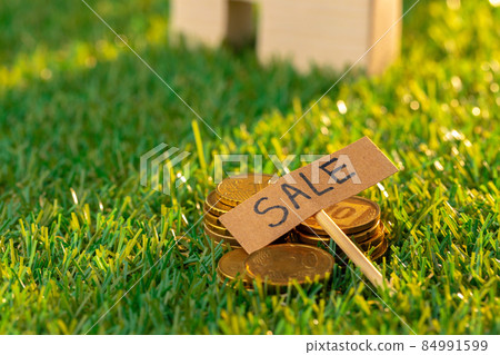 Wooden toy house on grass with sale sign Wooden toy house on grass with sale sign 84991599