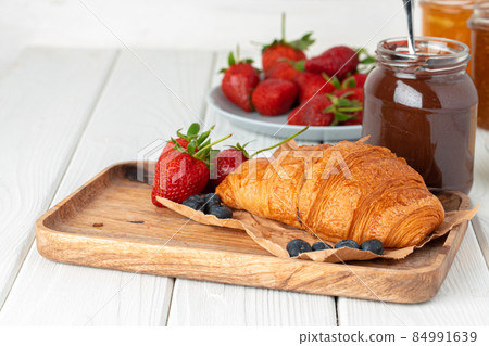 Fresh croissant decorated with berries on white wooden board 84991639