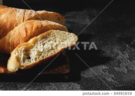 Sliced baguette bread on wooden board close up 84991659