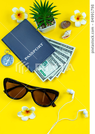 Flatlay accessories for summer vacation. Travel planning. Passport, money, sunglasses on a yellow background. Place for text. 84991798