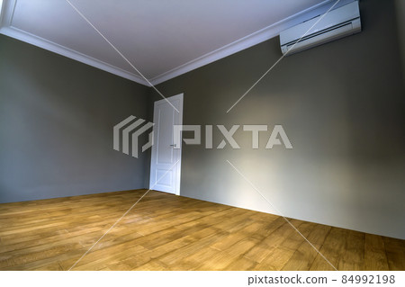 New renovated room interior with freshly painted walls, air conditioner, white door and wooden parquet floor New renovated room interior with freshly painted walls, air conditioner, white door and wooden parquet floor 84992198