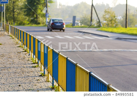 Blue and yellow fence dividing sidewalk from road Blue and yellow fence dividing sidewalk from road 84993581