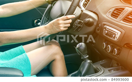 Beautiful tanned slim woman driver legs in a car. Girl in dress driving a car Beautiful tanned slim woman driver legs in a car. Girl in dress driving a car 84993600