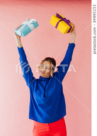 a 40-year-old woman holds gifts on a pink background a 40-year-old woman holds gifts on a pink background 84995153