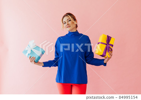 a 40-year-old woman holds gifts on a pink background a 40-year-old woman holds gifts on a pink background 84995154