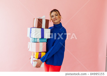 a 40-year-old woman holds gifts on a pink background a 40-year-old woman holds gifts on a pink background 84995155