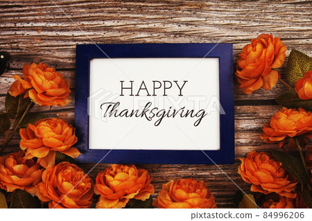 Happy Thanksgiving text in blue border frame with flower decoration on wooden background 84996206
