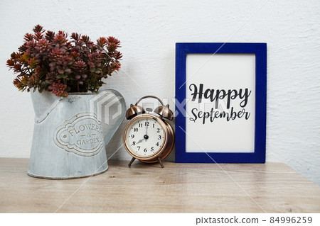 Happy September typography text with alarm clock and artificial plant decoration on wooden table and white wall background Happy September typography text with alarm clock and artificial plant decoration on wooden table and white wall background 84996259