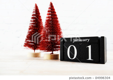 January 1st on the wooden calendar with little christmas tree on white brick wall background 84996304