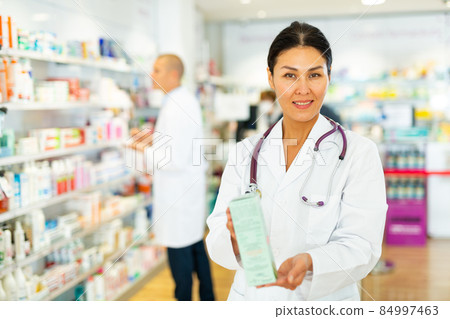 Female pharmacist offers medicine while standing in the trading floor of pharmacy 84997463