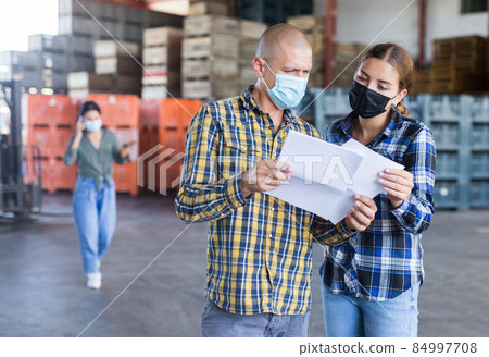 Man and young woman in masks talking about documentation Man and young woman in masks talking about documentation 84997708