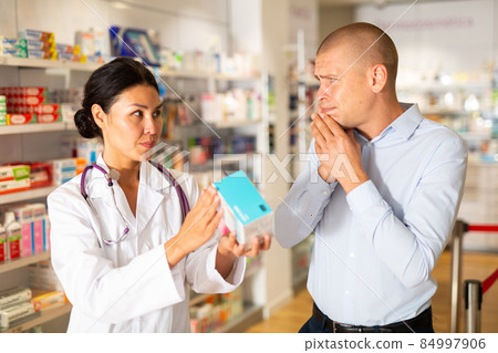 Female pharmacist helping man with toothache in drugstore 84997906