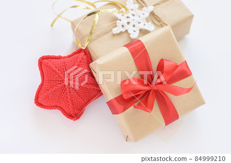 Christmas and New Years decorated gifts. Gift box wrapped in kraft paper with red ribbon. Red knitted heart. Box with jute cord and crocheted snowflake 84999210