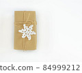 Christmas and New Years flatlay background. Gift box wrapped in kraft paper with jute cord. Decorated with a crocheted snowflake. Place for your text 84999212