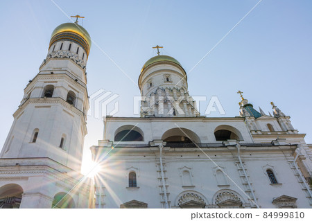 Ivan the Great Bell Tower, with Assumption Belfry on the right in Moscow Kremlin. Blue sky background with sunbeams 84999810