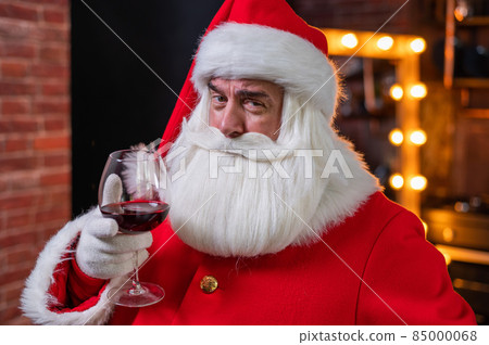Santa claus with a glass of red wine wishes merry christmas and says toast 85000068