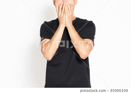 A man in a black T-shirt standing in front of a white background and making a surprised pose 85000109