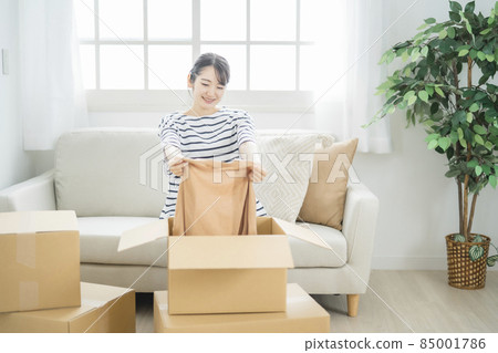 A woman looking inside a cardboard box A woman looking inside a cardboard box 85001786