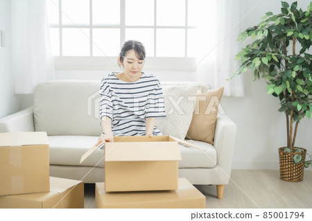A woman looking inside a cardboard box 85001794