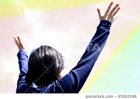 A young woman is looking up with her hands open under the sky A young woman is looking up with her hands open under the sky 85002096