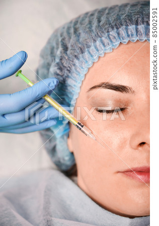 Close up of doctor cosmetologist hand making injection in female client cheek. Young woman receiving facial treatment at beauty salon. Concept of beauty, mesotheraphy and anti-aging procedure. Close up of doctor cosmetologist hand making injection in female client cheek. Young woman receiving facial treatment at beauty salon. Concept of beauty, mesotheraphy and anti-aging procedure. 85002591