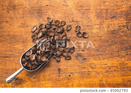 Sweet chocolate breakfast cereal flakes in scoop. Sweet chocolate breakfast cereal flakes in scoop. 85002793