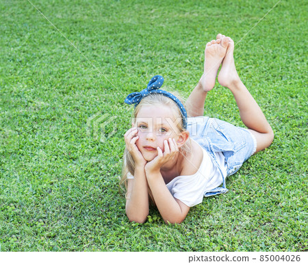 Little girl lying on green grass 85004026