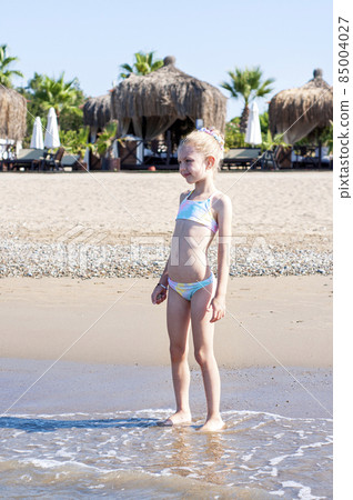 Little girl playing on the beach by the sea 85004027