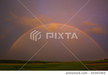 Lightning with with beautiful rainbow, fresh rain in the summer field landscape Lightning with with beautiful rainbow, fresh rain in the summer field landscape 85005468
