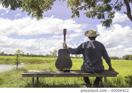 Back view of relax time.A man sitting in field playing acoustic guitar and see field view.outdoor park,Musical Instrument,photo Acoustic Music and lifestyle concept Back view of relax time.A man sitting in field playing acoustic guitar and see field view.outdoor park,Musical Instrument,photo Acoustic Music and lifestyle concept 85006422