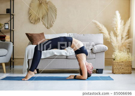 Young woman performing wheel pose during morning yoga practice 85006696