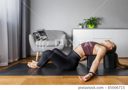 Young fitness woman doing morning yoga routine at home. Young fitness woman doing morning yoga routine at home. 85006715