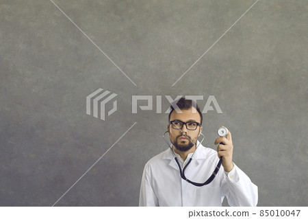 Doctor physician in spectacles holding stethoscope practicing medicine. Professional emergency healthcare, time for checkup examination and assistance service concept. Studio portrait shot 85010047