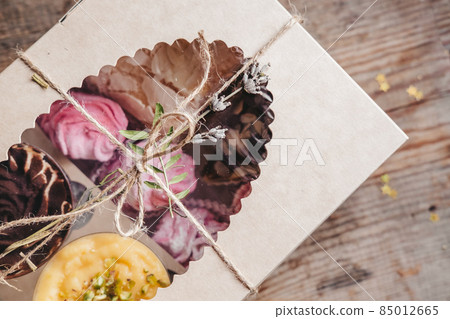 closed box with different cakes wrapped with thread, on a wooden background. Assorted cakes in a craft box closed box with different cakes wrapped with thread, on a wooden background. Assorted cakes in a craft box 85012665