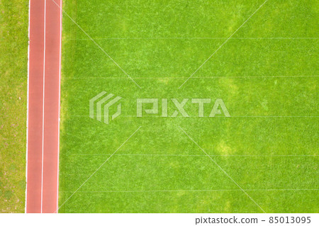 Aerial view of surface of green freshly cut grass on football stadium field with red running tracks in summer. Aerial view of surface of green freshly cut grass on football stadium field with red running tracks in summer. 85013095