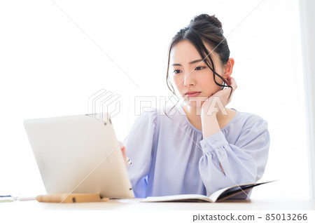 A woman with a difficult expression looking at the screen A woman with a difficult expression looking at the screen 85013266