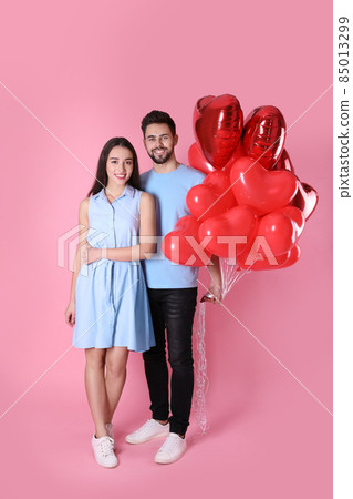 Happy young couple with gift box and heart shaped balloons isolated on white 85013299