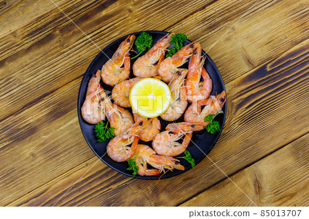 Red boiled prawns with lemon and parsley on wooden table. Top view Red boiled prawns with lemon and parsley on wooden table. Top view 85013707
