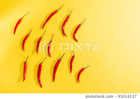Red chili peppers on a yellow background. Topview creative composition with copy space Red chili peppers on a yellow background. Topview creative composition with copy space 85014137