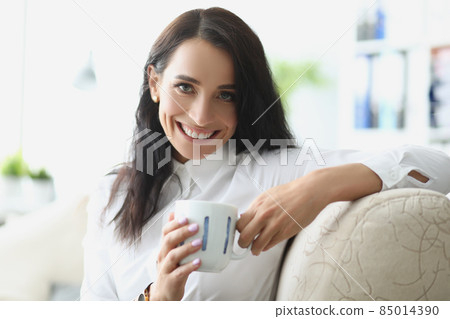 Beautiful brunette young woman chilling with cup of hot drink Beautiful brunette young woman chilling with cup of hot drink 85014390