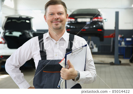 Qualified maintenance centre worker in special uniform posing on cars background Qualified maintenance centre worker in special uniform posing on cars background 85014422