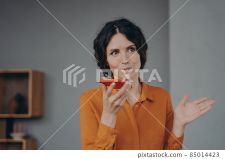 Beautiful brunette Italian businesswoman elegantly speaks on loudspeaker on mobile at home Beautiful brunette Italian businesswoman elegantly speaks on loudspeaker on mobile at home 85014423